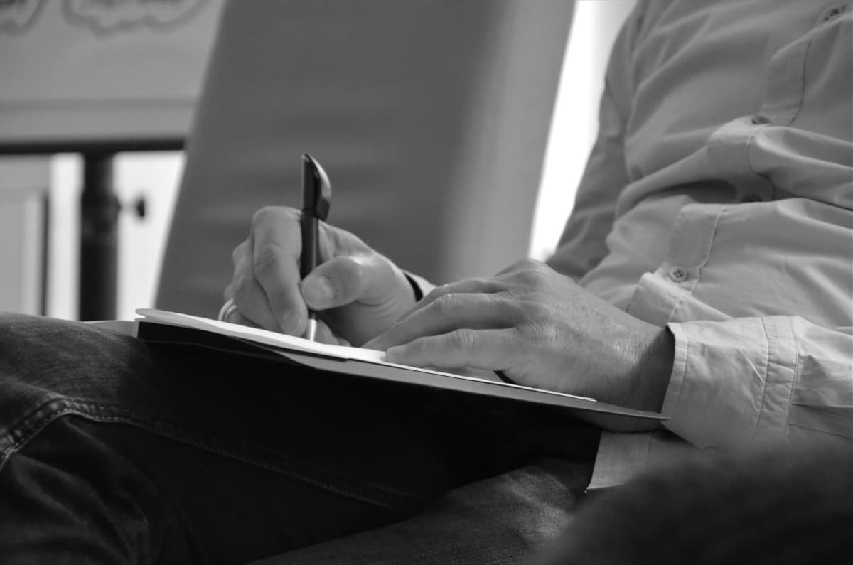 Close-up of hands writing notes, black and white